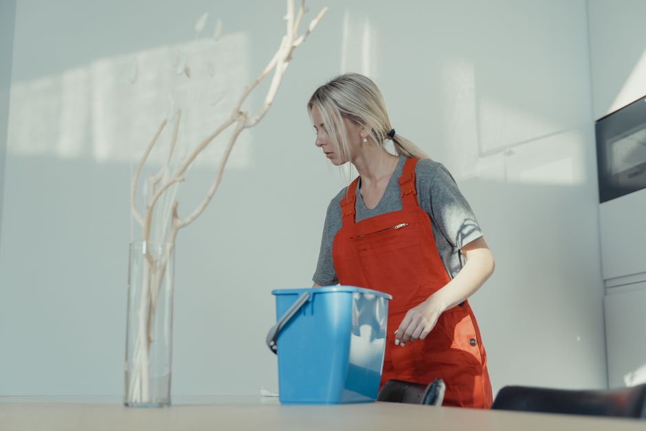 Professional house cleaner proudly standing in a sparkling clean living room